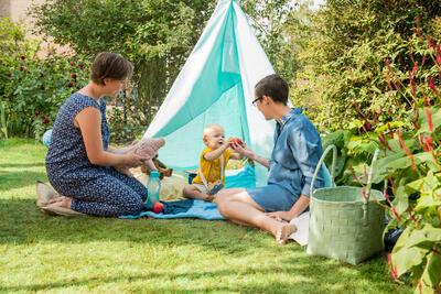 Twee mama's picknicken samen met hun zoontje buiten voor een tent